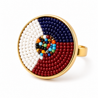 The image features a colorful ring with a circular design. The ring has a gold-tone band and an intricate arrangement of small beads in various colors, including red, white, blue, and several other vibrant hues, forming a pattern in the center.
